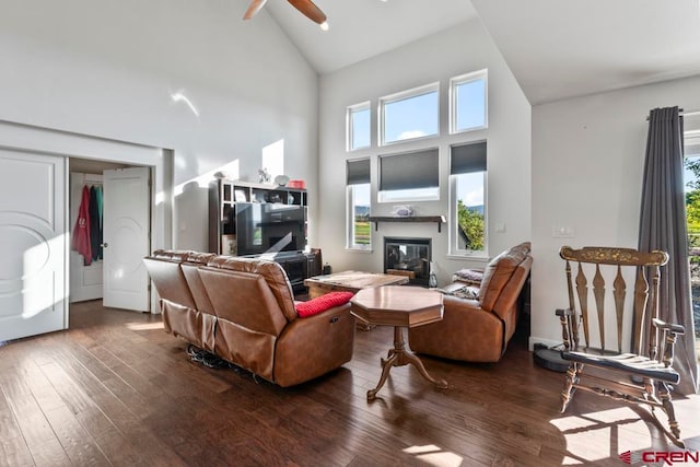 living room with ceiling fan, dark hardwood / wood-style floors, and high vaulted ceiling