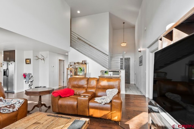 living room with a towering ceiling and dark wood-type flooring