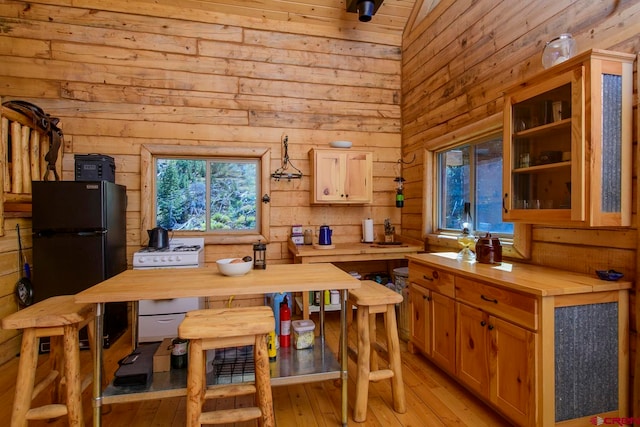 kitchen with light hardwood / wood-style floors, white range with gas stovetop, wood walls, lofted ceiling, and wood counters