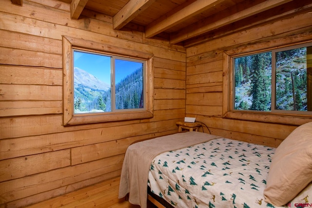 bedroom featuring a mountain view, wood ceiling, beam ceiling, wood-type flooring, and wooden walls