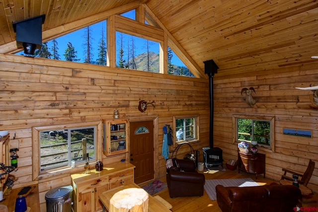 living room with wood ceiling, hardwood / wood-style floors, a wood stove, and a wealth of natural light