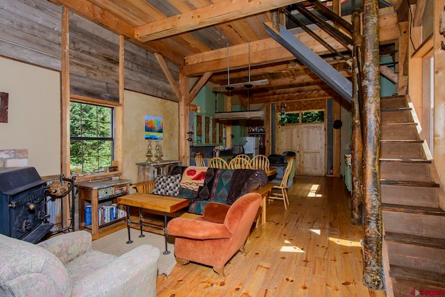 living room with wood ceiling, light hardwood / wood-style floors, a wood stove, a high ceiling, and beam ceiling