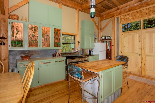 kitchen featuring wood counters, beam ceiling, white fridge, a kitchen island, and light hardwood / wood-style flooring