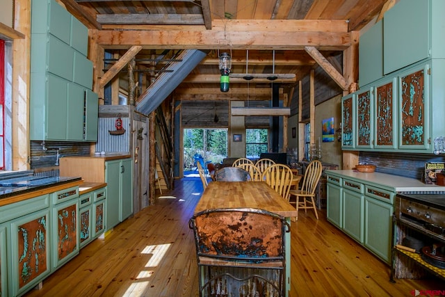 kitchen featuring light wood-type flooring, green cabinets, beamed ceiling, and tasteful backsplash