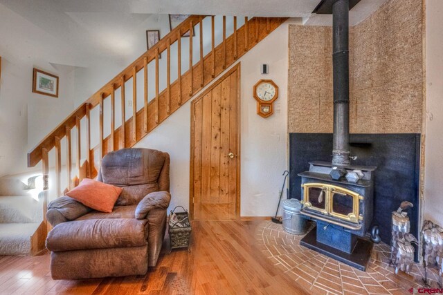 living area with a wood stove, a towering ceiling, and hardwood / wood-style floors