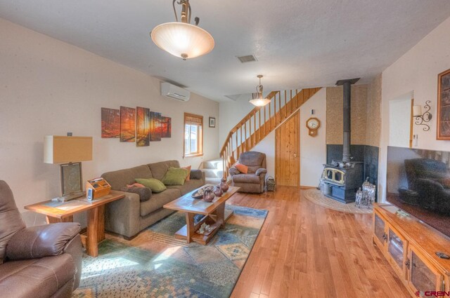 living room with light hardwood / wood-style floors, a wood stove, and a wall unit AC