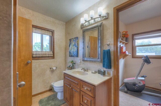 bathroom featuring vanity, tile patterned flooring, toilet, and a textured ceiling