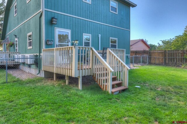 rear view of house with a wooden deck and a lawn