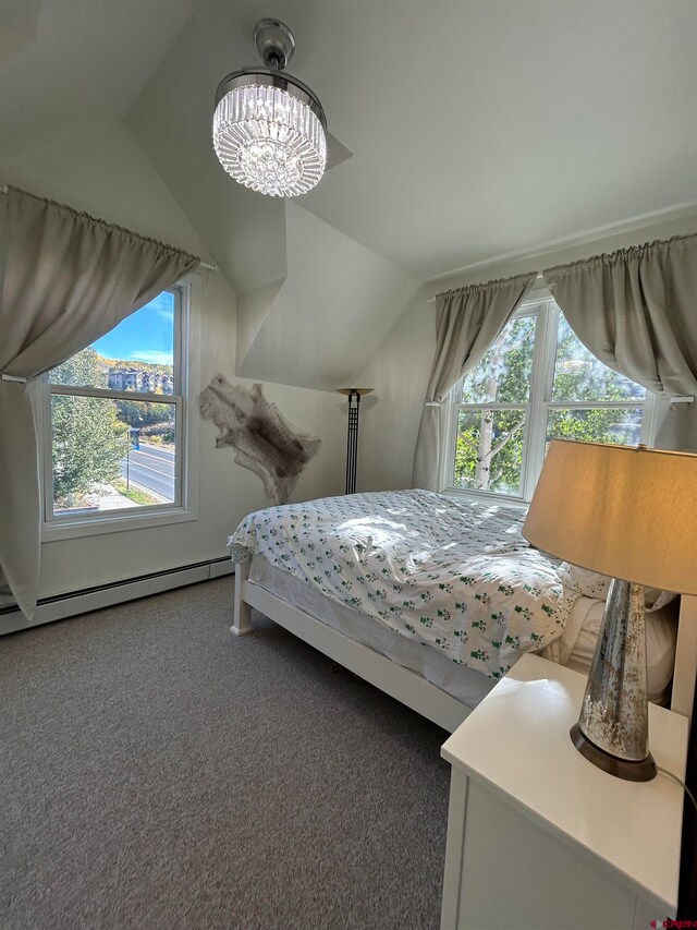 carpeted bedroom with a baseboard radiator, vaulted ceiling, multiple windows, and an inviting chandelier