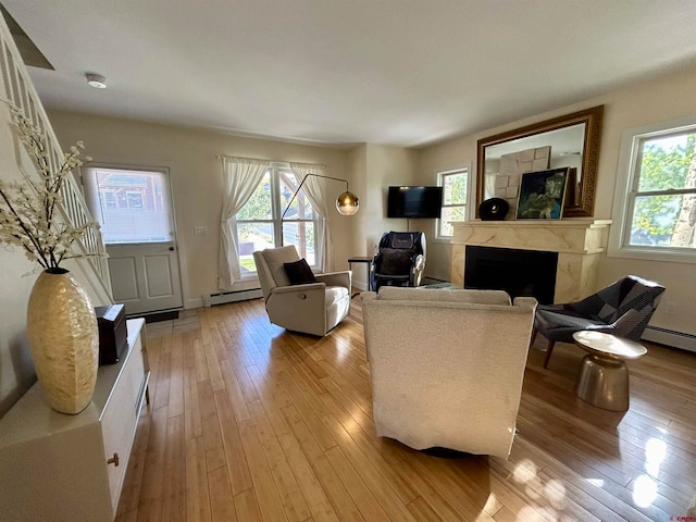 living room with a wealth of natural light, a premium fireplace, and a baseboard heating unit