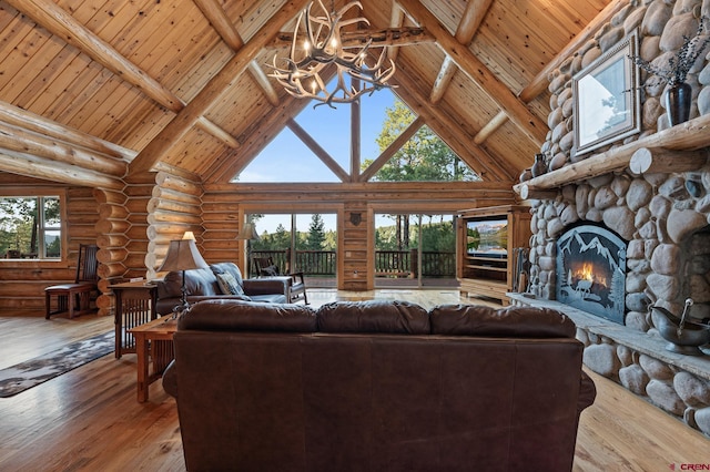 living room with high vaulted ceiling, a chandelier, hardwood / wood-style floors, and a stone fireplace