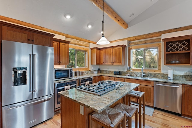 kitchen with lofted ceiling with beams, a center island, a breakfast bar area, sink, and appliances with stainless steel finishes