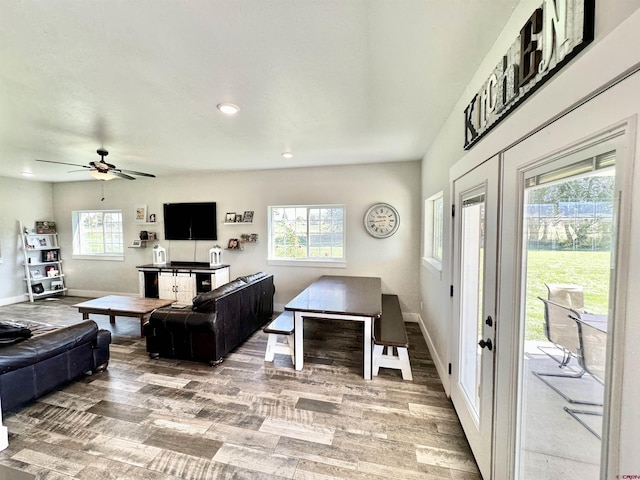 living area featuring baseboards, a ceiling fan, and light wood finished floors