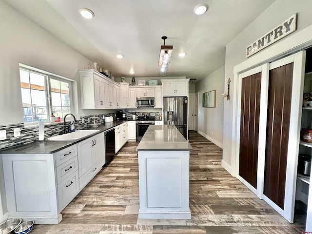 kitchen featuring white cabinets, a sink, stainless steel appliances, and dark countertops