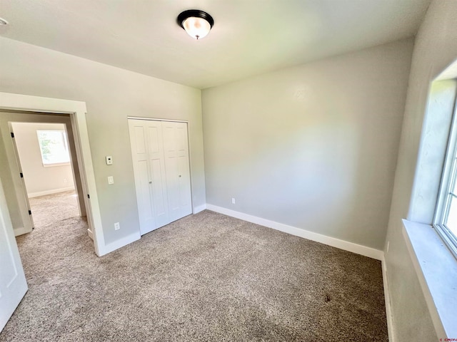 unfurnished bedroom with light carpet and a closet