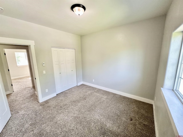 unfurnished bedroom with carpet floors, baseboards, and a closet