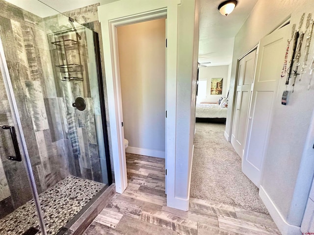 bathroom featuring toilet, hardwood / wood-style floors, and an enclosed shower