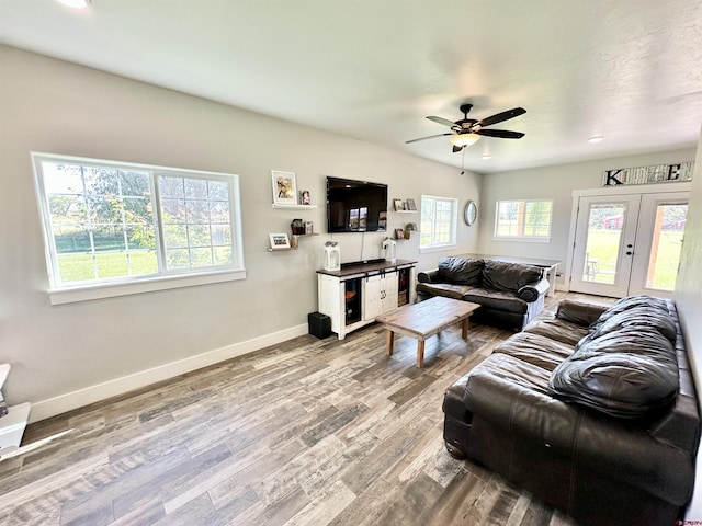 living area featuring baseboards, wood finished floors, french doors, and a ceiling fan