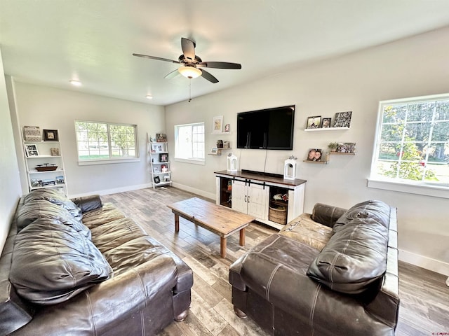 living area with baseboards, wood finished floors, and a ceiling fan