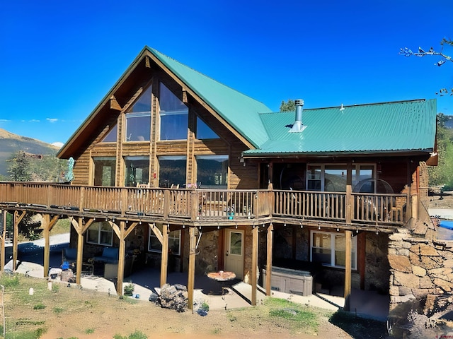 back of property with a deck with mountain view and a patio area