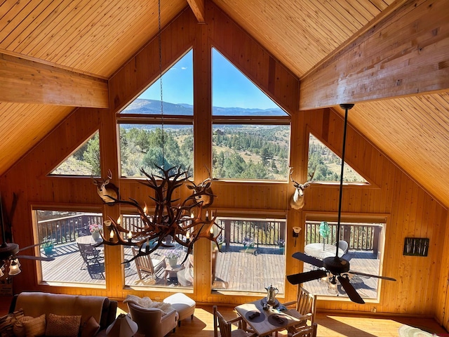 living room with wood ceiling, a mountain view, ceiling fan, hardwood / wood-style flooring, and wooden walls