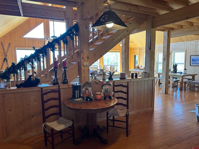 dining space with wooden ceiling, wood walls, lofted ceiling with beams, and hardwood / wood-style flooring
