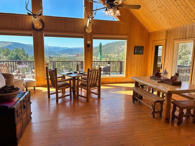 dining space featuring wood walls, ceiling fan, a mountain view, and a wealth of natural light