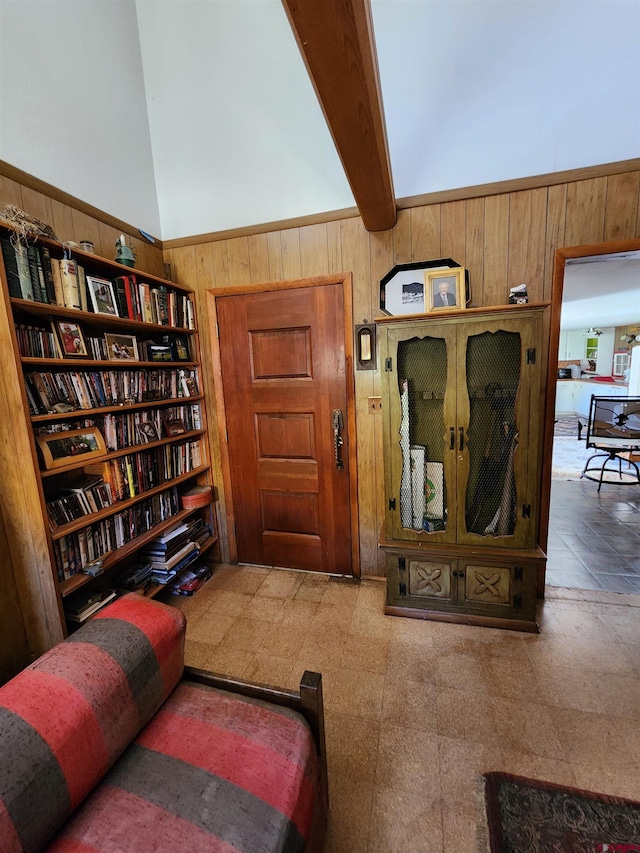 living area with a towering ceiling, wood walls, and beam ceiling