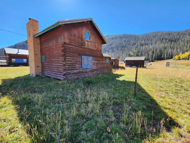 view of side of property with a storage shed, a yard, and a mountain view