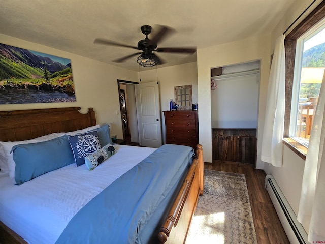 bedroom featuring a closet, ceiling fan, baseboard heating, and dark wood-type flooring