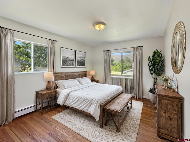 bedroom with wood-type flooring and a baseboard radiator