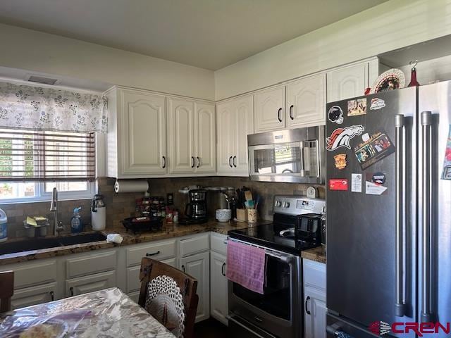 kitchen featuring stainless steel appliances, white cabinetry, tasteful backsplash, and sink