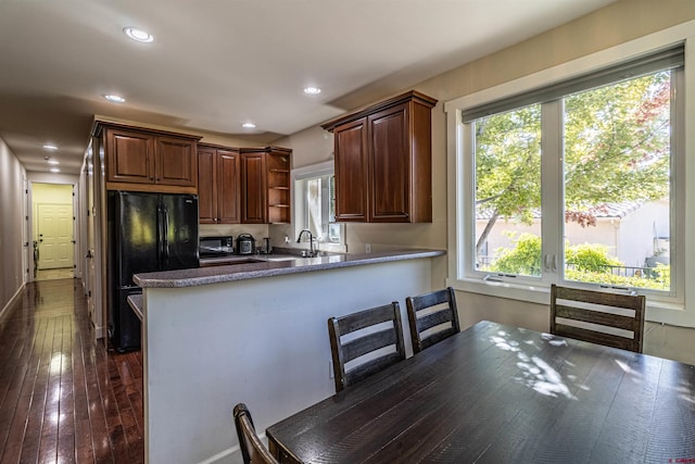 kitchen featuring black fridge, sink, dark hardwood / wood-style flooring, and kitchen peninsula