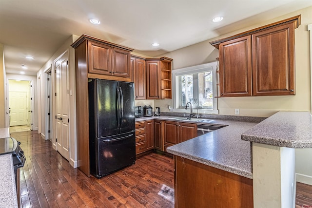 kitchen with black fridge, dark wood-type flooring, sink, stove, and kitchen peninsula