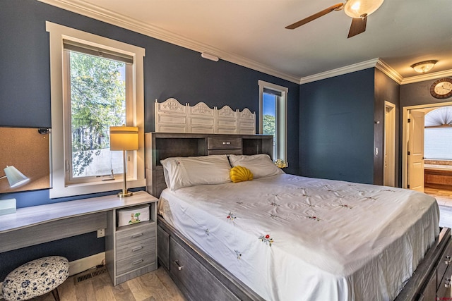 bedroom with crown molding, connected bathroom, ceiling fan, and hardwood / wood-style flooring