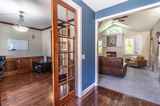 interior space featuring dark wood-type flooring, ceiling fan, vaulted ceiling, and a fireplace