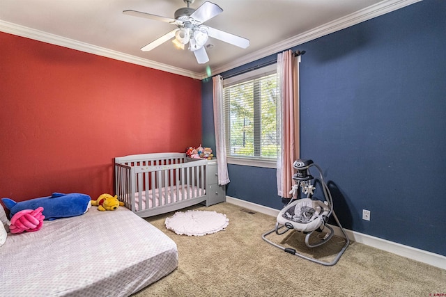 bedroom with ceiling fan, a crib, crown molding, and carpet flooring