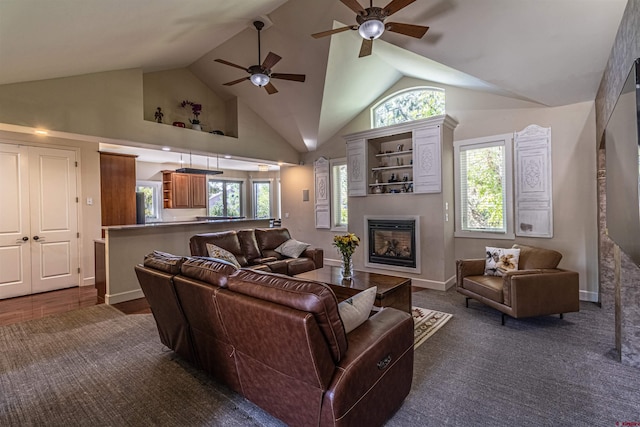 living room with a healthy amount of sunlight, dark hardwood / wood-style floors, ceiling fan, and high vaulted ceiling