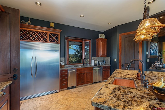 kitchen with decorative light fixtures, appliances with stainless steel finishes, sink, and decorative backsplash