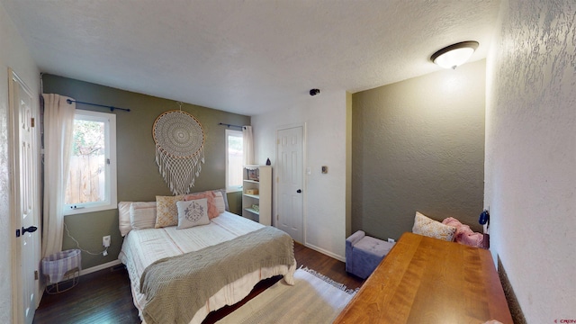 bedroom with a textured ceiling and dark hardwood / wood-style flooring