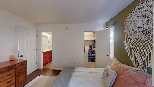 bedroom featuring dark hardwood / wood-style floors, a walk in closet, ensuite bathroom, and a closet