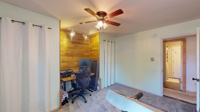 carpeted office with wooden walls, ceiling fan, a textured ceiling, and rail lighting