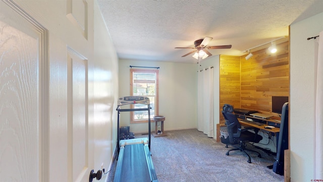 office area with rail lighting, carpet floors, a textured ceiling, ceiling fan, and wooden walls