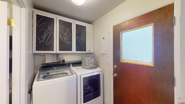 washroom with a textured ceiling, separate washer and dryer, and cabinets