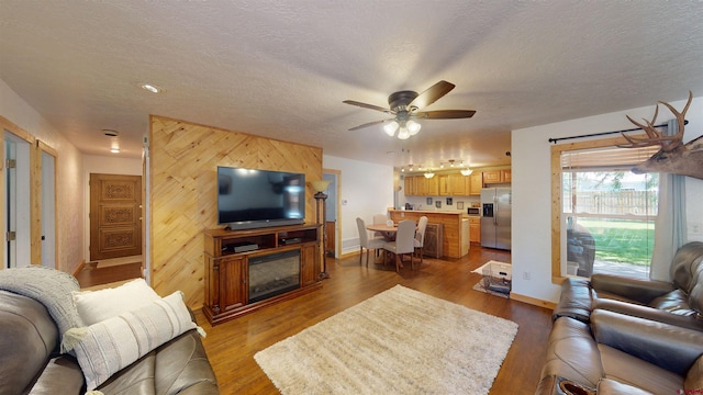 living room with a textured ceiling, wood walls, and light hardwood / wood-style flooring