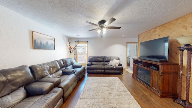 living room with ceiling fan, a textured ceiling, and dark hardwood / wood-style floors