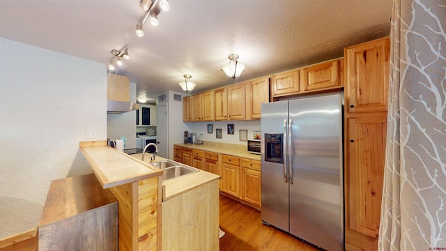 kitchen with sink, kitchen peninsula, light hardwood / wood-style flooring, stainless steel fridge with ice dispenser, and light brown cabinetry