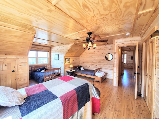 bedroom with ceiling fan, wooden walls, wooden ceiling, light wood-type flooring, and vaulted ceiling