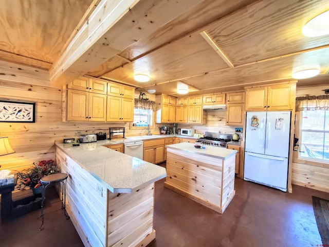 kitchen with wood walls, a kitchen island, stainless steel appliances, light brown cabinetry, and sink