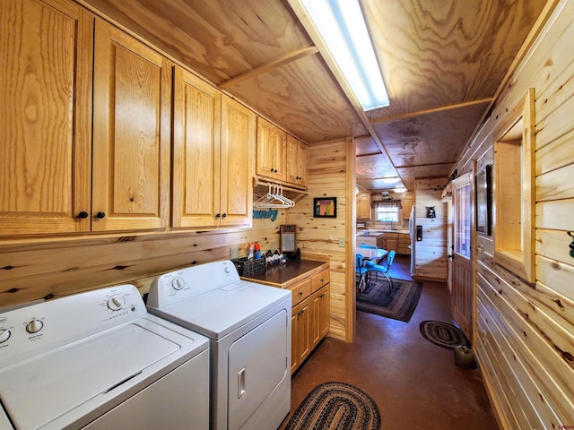 laundry room featuring cabinets, wood walls, and washing machine and dryer